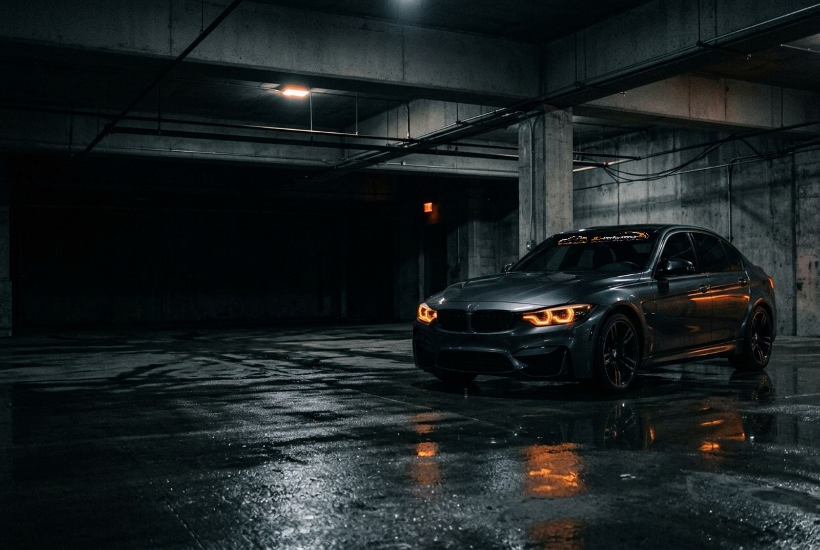 Voiture sombre aux phares orange dans un garage de nuit